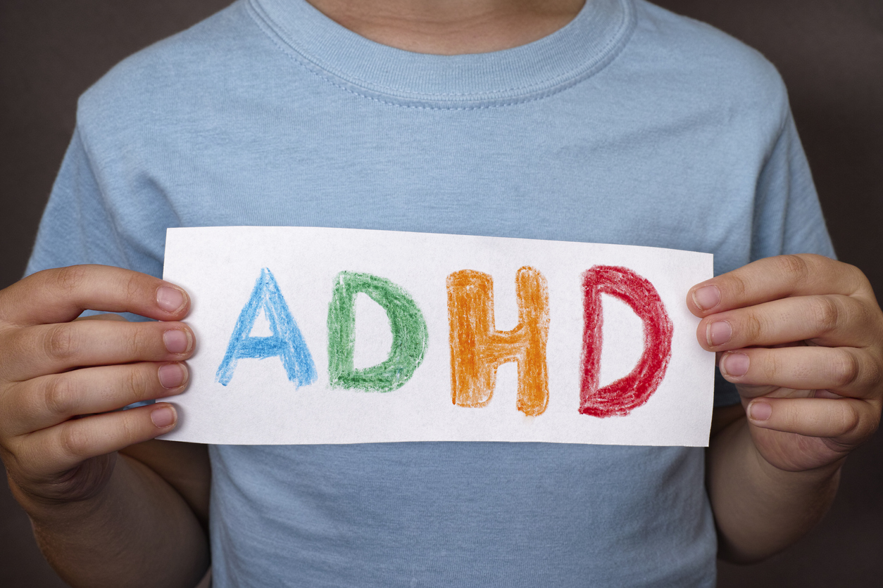 Young boy holds ADHD text written on sheet of paper