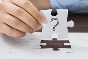 Close-up Of Person Hand Holding Puzzle With Question Mark Sign