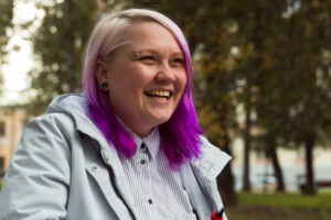 woman with blonde and purple hair smiling outdoors