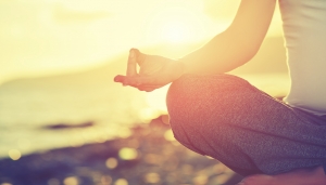 Yoga concept. hand woman practicing lotus pose on the beach at sunset